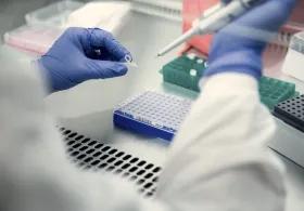 The gloved hands of a scientist conducting testing in a laboratory.