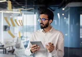 Man with clipboard reading notes on message board