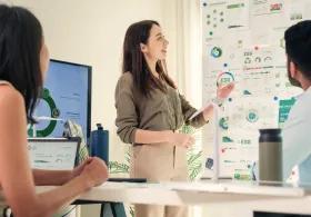 Group of people discussing charts and tables on a wall