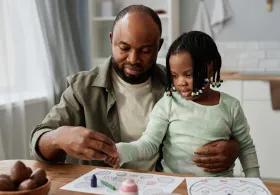 Man and girl drawing on paper at a table