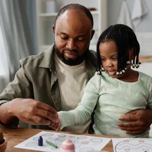 Man and girl drawing on paper at a table