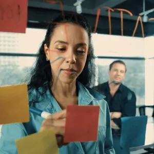 People looking at post-it notes on a wall in office