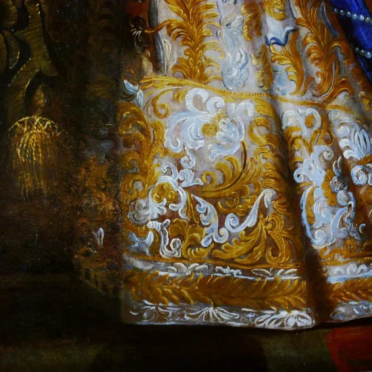 A detailed section of a painting showing the intricate embroidery and embellishments on Queen Elizabeth I’s dress