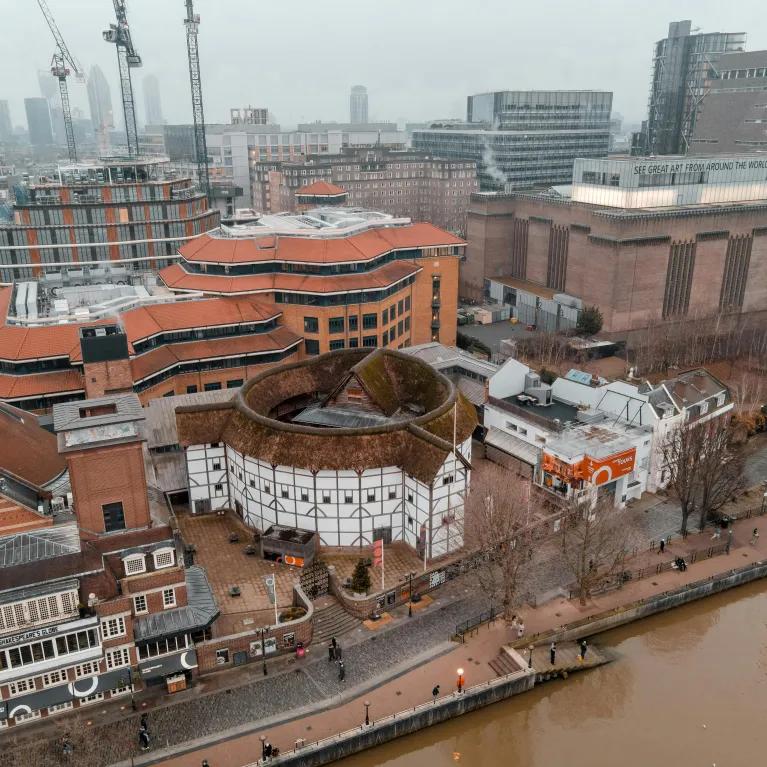 A bird’s-eye view of London with Shakespeare’s Globe at the centre, surrounded by other buildings under a foggy sky