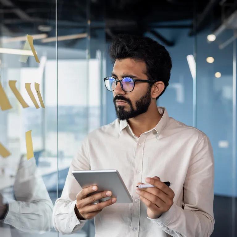 Man with clipboard reading notes on message board