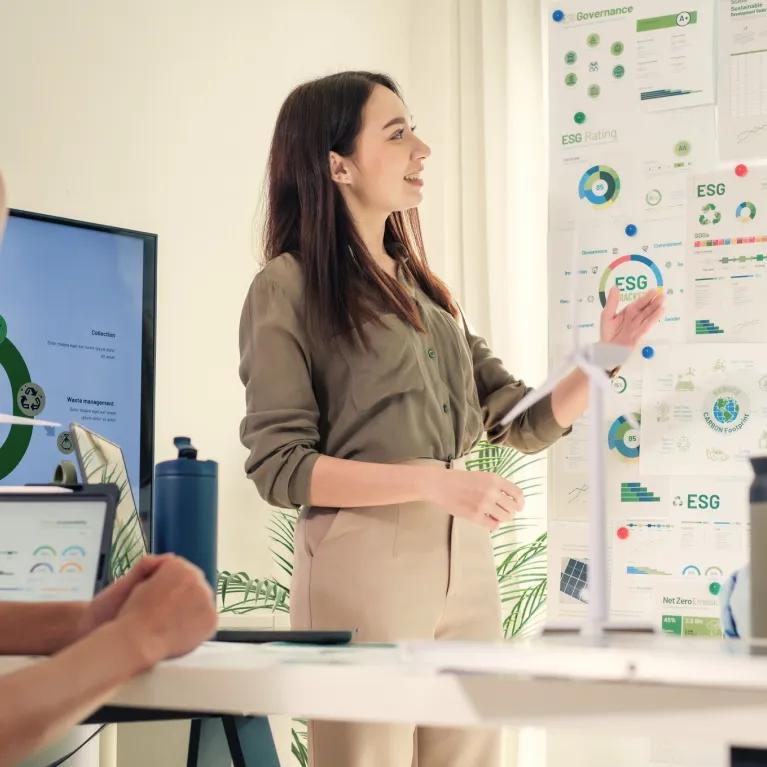Group of people discussing charts and tables on a wall