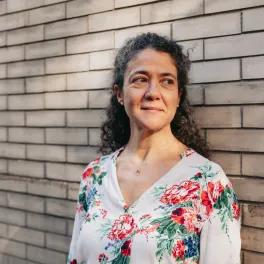 Woman looking slightly off camera stood against a wall